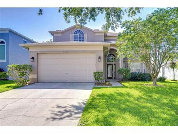 Charming two-story home featuring a well-manicured lawn, a two-car garage, and mature landscaping at 1632 Gray Bark Dr, Oldsmar, FL 34677