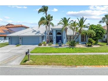Charming single-story home featuring lush landscaping, a three-car garage, and a welcoming front lawn at 5104 E Longboat Blvd, Tampa, FL 33615