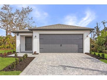 Charming single-story home with a gray garage door and a beautifully paved driveway at 1721 Shevlin St, North Port, FL 34286