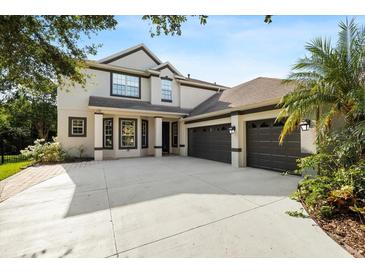 Two story home with a large driveway, three-car garage, and manicured landscaping at 20403 Walnut Grove Ln, Tampa, FL 33647