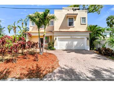 Charming two-story home with lush landscaping, palm trees, brick paver driveway, and a two car garage at 2410 W North A St # 2, Tampa, FL 33609