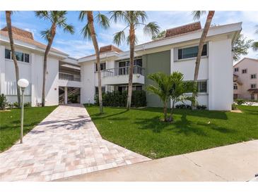 Charming condo building showcasing lush tropical landscaping and a welcoming brick walkway at 311 Island Way # 101, Clearwater Beach, FL 33767