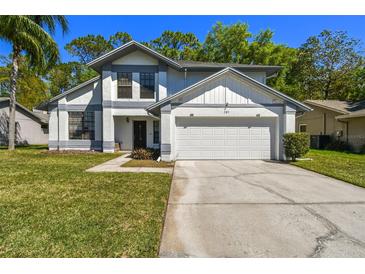 Charming two-story home featuring a two-car garage, well-manicured lawn, and classic architectural details at 389 Waterford W Cir, Tarpon Springs, FL 34688