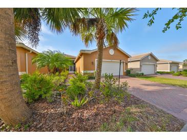 Charming single-story home with a brick driveway and lush tropical landscaping at 4961 Marble Springs Cir, Wimauma, FL 33598