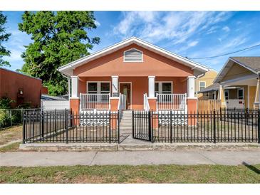 Charming bungalow with a black metal fence, orange stucco, and a covered front porch at 6414 N Central Ave, Tampa, FL 33604