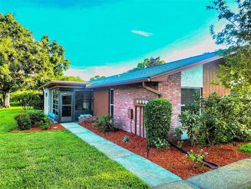 Charming single-story home featuring brick accents, a screened-in porch, and a well-maintained front yard with lush landscaping at 2241 Shelly Dr # D, Palm Harbor, FL 34684