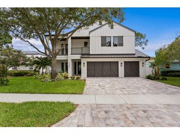Stunning two-story modern farmhouse-style home with a manicured lawn and three-car garage at 3406 W Alline Ave, Tampa, FL 33611