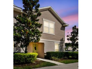 Charming townhome featuring neutral siding, manicured lawn, and welcoming entrance, bathed in a pleasant evening light at 5022 Chipotle Ln, Wesley Chapel, FL 33544