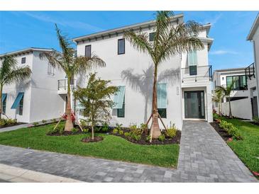 Modern, two-story home featuring a clean white exterior, palm trees, and manicured landscaping at 6023 Cat Claw Ln, Bradenton, FL 34210