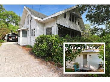 Charming two-story home with white siding, a carport, and a quaint guest house surrounded by lush greenery at 1107 S Prospect Ave, Clearwater, FL 33756
