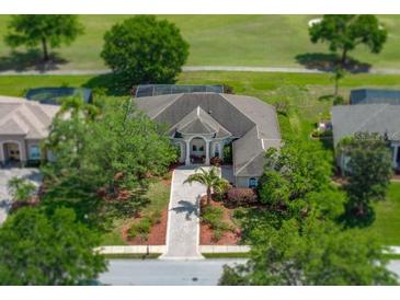 Stunning aerial view of home with golf course in the background; circular drive, mature landscaping at 13538 Thoroughbred Dr, Dade City, FL 33525