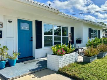 Inviting front porch with a blue door, beautiful plants and a cozy seating area at 14019 89Th Ave, Seminole, FL 33776