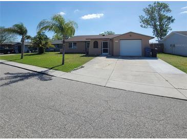 Charming single-story home with a well-maintained lawn and a two-car garage at 2110 Society Dr, Holiday, FL 34691