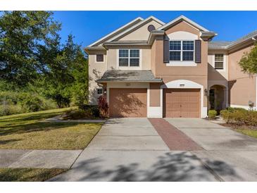 Two-story townhome boasts attached garages, neutral stucco, and meticulously maintained landscaping at 26517 Castleview Way, Wesley Chapel, FL 33544