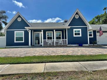 Charming blue home with a quaint front porch and brick paved driveway at 3000 Tangerine Ter, Palm Harbor, FL 34684