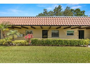 Charming condo with a red tile roof, complemented by lush landscaping and a well-manicured lawn at 1701 Pinehurst Rd # 31D, Dunedin, FL 34698