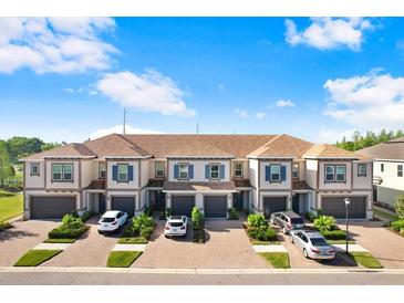 Townhome exterior featuring blue shutters, garages and brick driveways set under a bright blue sky at 18737 Noble Caspian Dr, Lutz, FL 33558
