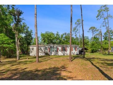 Single story home with an attached carport and mature trees in a sprawling yard at 7537 Old Pasco Rd, Wesley Chapel, FL 33544