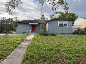 Charming single-story home with gray siding, a red front door and a small, partially-overgrown front yard at 1902 W Aileen St, Tampa, FL 33607