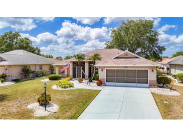Charming single-story home with well-maintained landscaping, screened garage, and cozy front porch at 2018 E Del Webb Blvd, Sun City Center, FL 33573