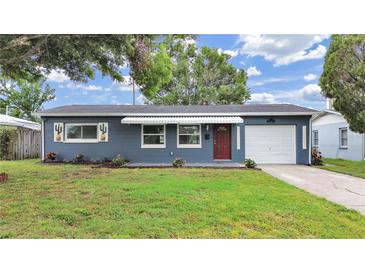 Charming one-story home with blue exterior, awning, red door, manicured lawn and single car garage at 5772 4Th N Ave, St Petersburg, FL 33710
