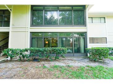 Condo exterior featuring large glass enclosed patios, trimmed shrubs, and natural surroundings at 6006 Laketree Ln # K, Temple Terrace, FL 33617