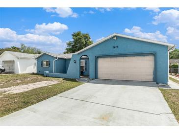 Exterior view of light blue single-story home with attached two-car garage and concrete driveway at 7426 Cay Dr, Port Richey, FL 34668