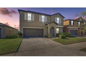 Two-story home boasts a spacious driveway, neutral tones, and well-maintained landscaping at 11476 Sage Canyon Dr, Riverview, FL 33578