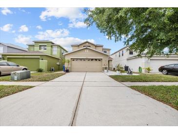 Charming two-story home with a beige exterior, a wide driveway, and well-maintained landscaping at 12107 Fox Bloom Ave, Gibsonton, FL 33534