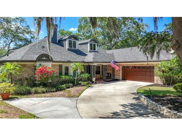 Charming single-story home with brick accents, dormer windows, mature landscaping, and an attached two-car garage at 213 Sheffield E Cir, Palm Harbor, FL 34683