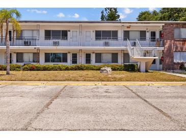 A daytime view of a two-story apartment building with ample parking, landscaping, and staircase access to the units at 2366 Shelley St # 7, Clearwater, FL 33765