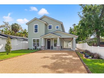 Charming two-story home featuring light green siding, gravel driveway, and a convenient covered parking area at 3505 N Dartmouth Ave, Tampa, FL 33603