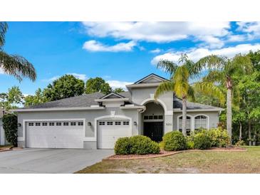 Charming single-story home features a well-manicured lawn, three-car garage, and arched entryway at 8202 Pinewood Run Ct, Tampa, FL 33647