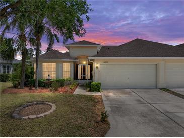 Beautiful home with a well-manicured lawn, a two-car garage, mature trees, and a lovely front garden at sunset at 10324 Chatuge Dr, San Antonio, FL 33576