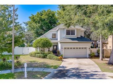 Charming two-story home featuring a well-manicured lawn, mature trees, and a two-car garage at 11386 Churchhill Trl, Seminole, FL 33772