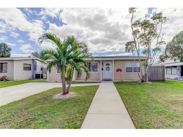 Charming home with a well-manicured lawn, a palm tree, and a welcoming walkway leading to the front door at 1142 56Th N Ave, St Petersburg, FL 33703