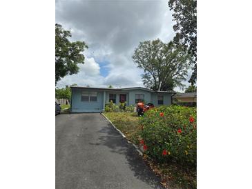 Charming single-story home with a driveway, lush lawn, and colorful flowers, creating curb appeal at 1607 Stevensons Dr, Clearwater, FL 33755