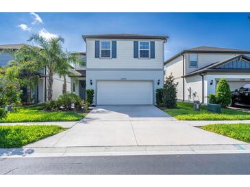 Charming two-story home featuring a two-car garage, manicured lawn, and beautiful landscaping at 20472 Monza Loop, Land O Lakes, FL 34638