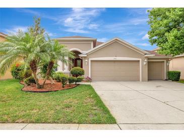 Charming tan home with well-manicured front yard, featuring a two-car garage and inviting curb appeal at 3510 Hickory Hammock Loop, Wesley Chapel, FL 33544