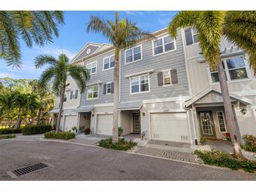Attractive townhome exterior featuring stylish gray siding, white trim, and lush palm tree landscaping at 5912 Anchorage S Way, St Petersburg, FL 33712