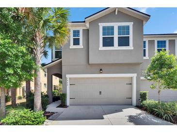 Charming townhouse featuring a two-car garage and meticulously landscaped front yard with lush greenery at 5922 Grand Sonata Ave, Lutz, FL 33558