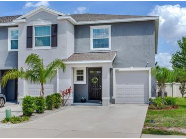 Charming two-story townhome featuring a well-maintained lawn, one-car garage, and welcoming front entrance at 2882 Suncoast Plains Dr, Odessa, FL 33556