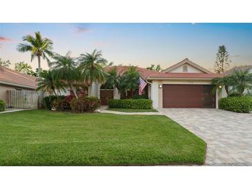Charming single-story home featuring a tile roof, brick driveway, lush landscaping, and a well-manicured lawn at 772 Live Oak Ne Ter, St Petersburg, FL 33703