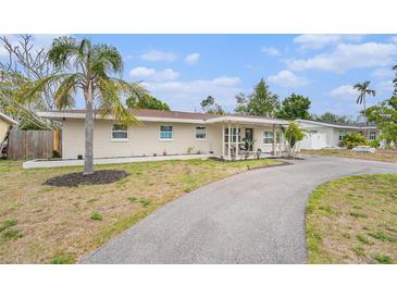 Charming single-story home featuring a circular driveway and a well-maintained front yard with a mature palm tree at 831 72Nd N Ave, St Petersburg, FL 33702