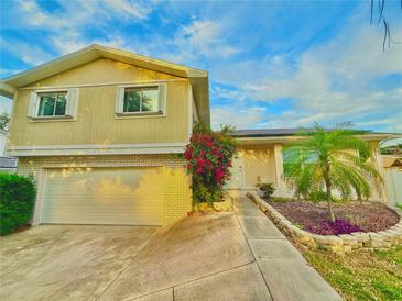 Two-story home with a neutral exterior, attached garage and colorful flowering shrub in the front at 12432 81St Ct, Seminole, FL 33772