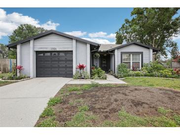 Charming single-story home with a gray exterior, a well-maintained lawn, and an attached garage at 1705 Cinnabar Ct, Brandon, FL 33510