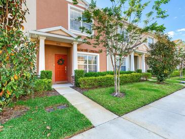 Charming townhome exterior featuring a red front door, manicured lawn, and fresh landscaping at 30340 Elderwood Dr, Wesley Chapel, FL 33543