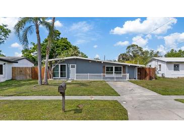 Charming single-story home featuring a well-maintained lawn, gray exterior, and a welcoming white-picket fence at 4003 W Bay Ave, Tampa, FL 33616