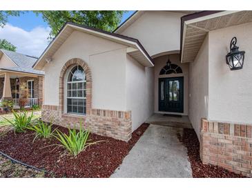 Front entrance featuring arched window and brick accents, leading to a welcoming front door at 6711 Thackston Dr, Riverview, FL 33578