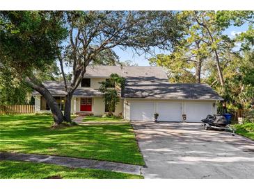Charming two-story home with a three-car garage, mature trees, and manicured lawn at 1800 Salem Ct, Dunedin, FL 34698